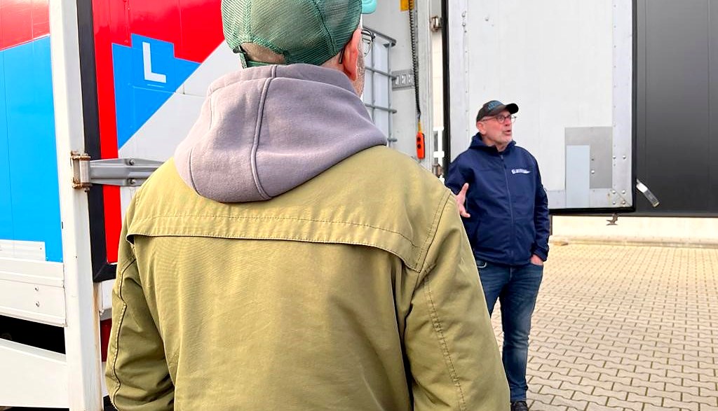 Instructeur geeft uitleg aan een cursist bij de laadruimte van een trailer