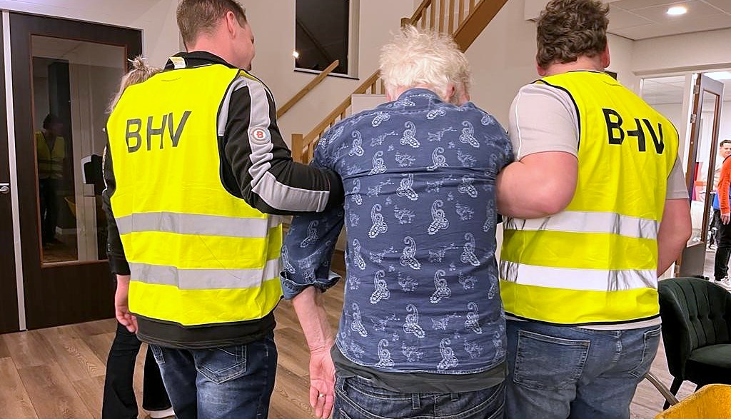 Twee cursisten in BHV-hesjes begeleiden een slachtoffer tijdens een oefening