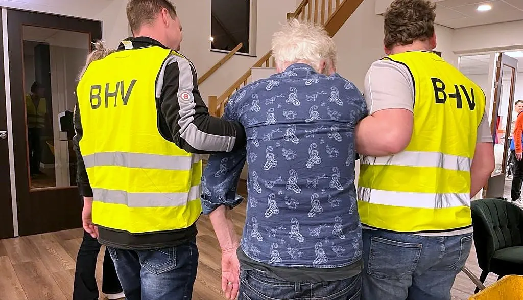 Twee cursisten in BHV-hesjes begeleiden een slachtoffer tijdens een oefening