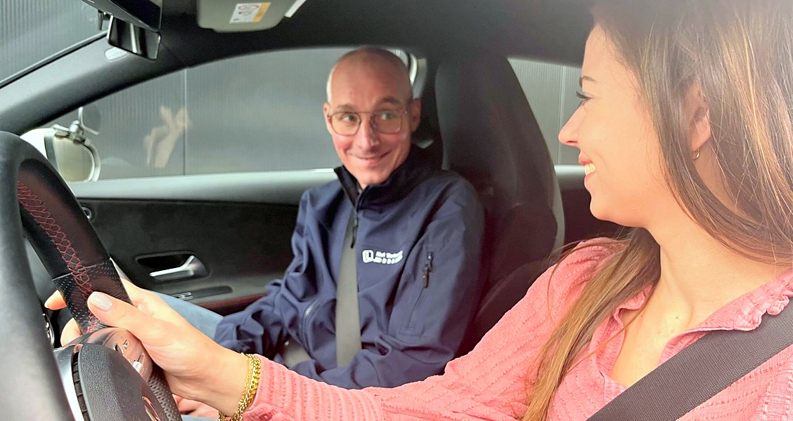 Instructeur en leerling lachen tijdens een autorijles